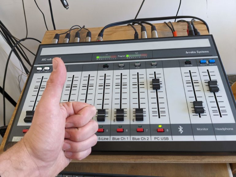 Person giving a thumbs up in front of a mixing board that is new at the time